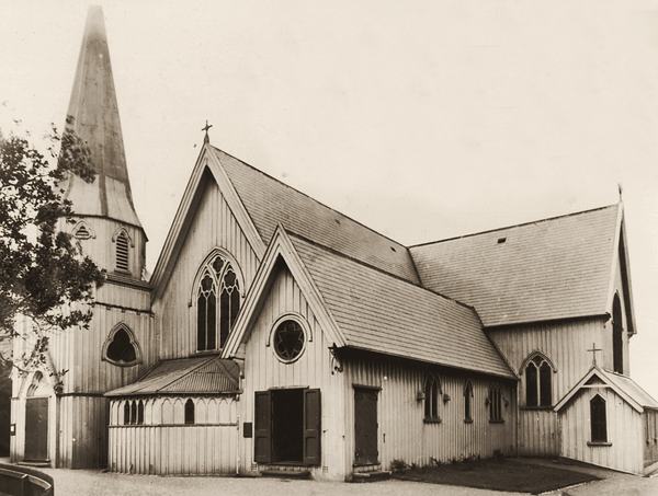 A white timber Gothic church with a tall spire and steep gables.