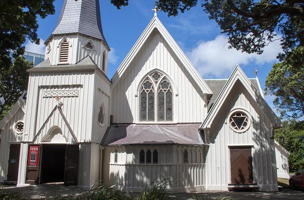 The same white timber church in sunshine, under a blue sky.