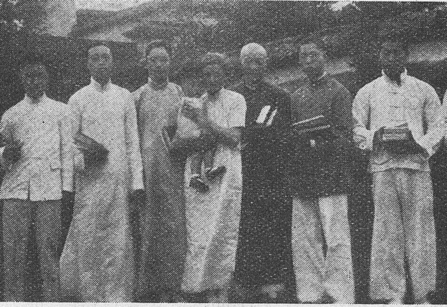 A row of young Chinese men and women in long gowns and jackets, several holding books.