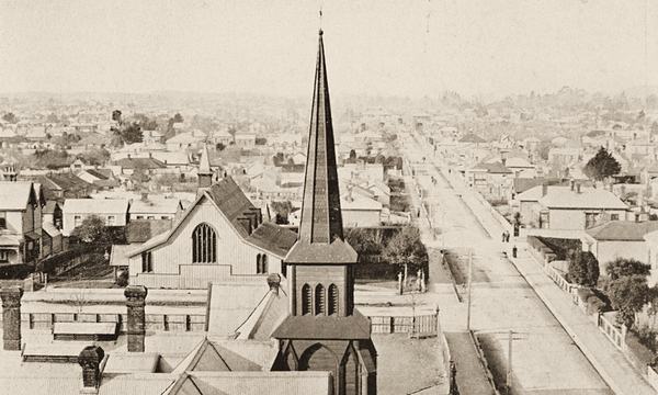 Looking down a long straight suburban street over rooftops, with two church spires in the foreground.