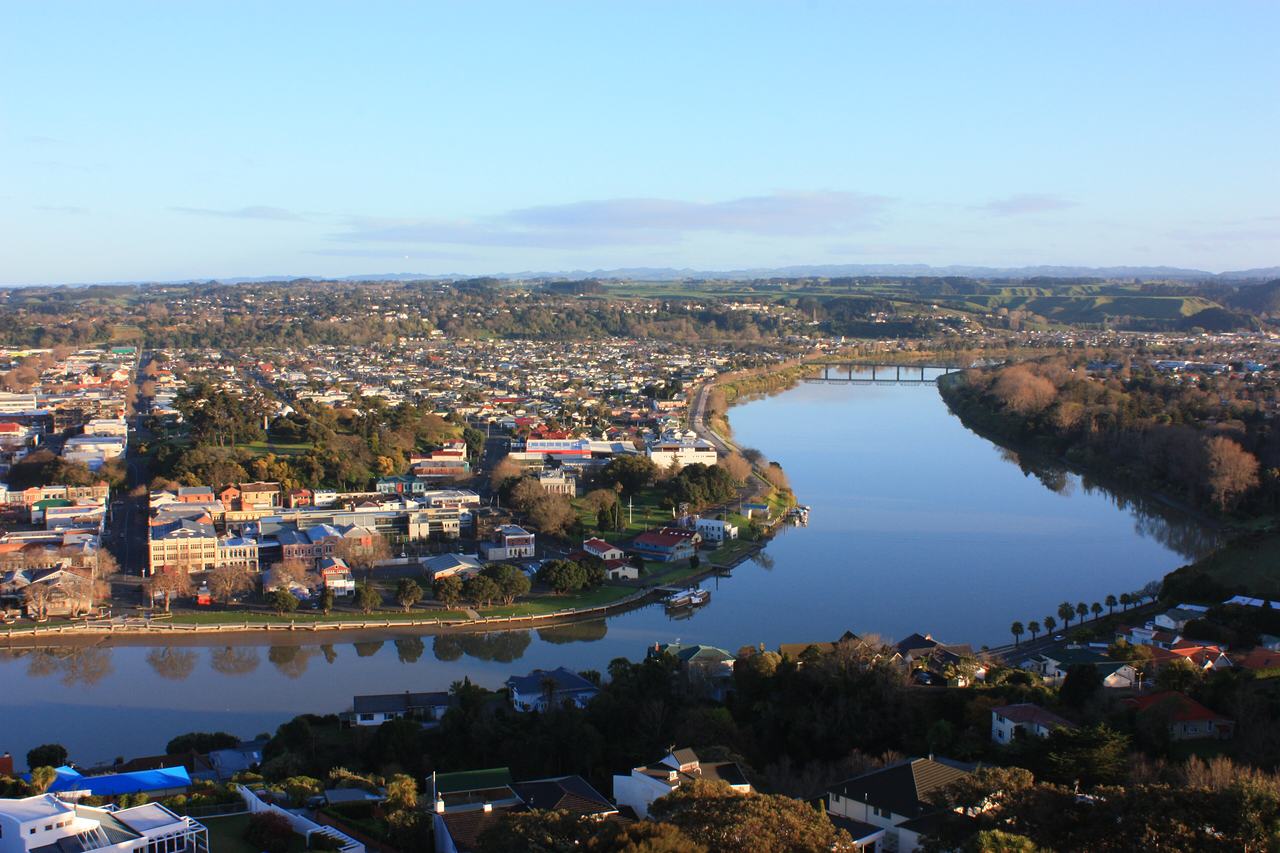 Early morning over Whanganui: the river curves through the town towards a bridge, in low golden light.